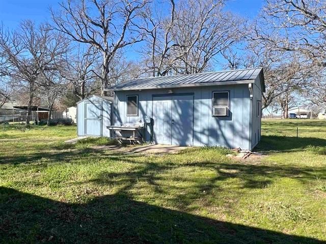 rear view of property with a storage unit and a lawn