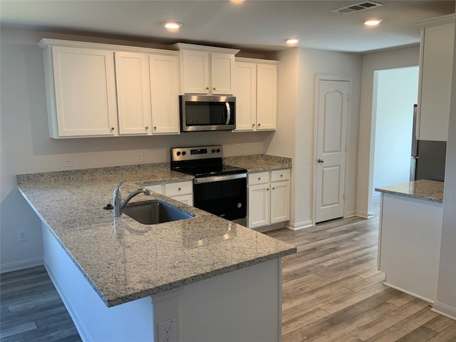 kitchen with white cabinetry, appliances with stainless steel finishes, and light stone countertops