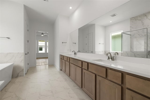 bathroom with tile walls, ceiling fan, separate shower and tub, and vanity