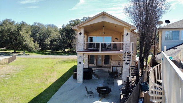 rear view of property featuring a balcony, a fire pit, a patio area, and a lawn