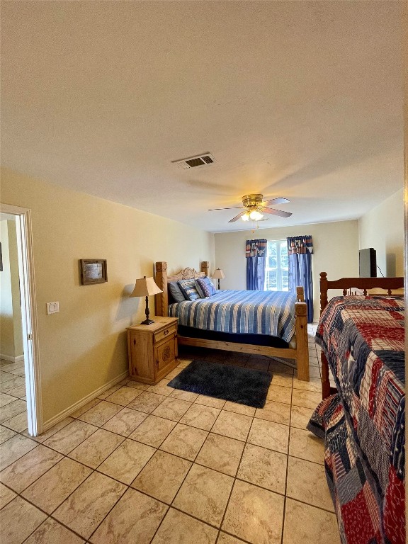 tiled bedroom featuring a textured ceiling and ceiling fan