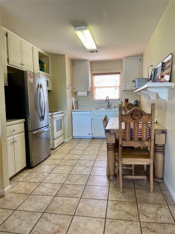 kitchen featuring light tile patterned floors, white appliances, white cabinetry, and sink