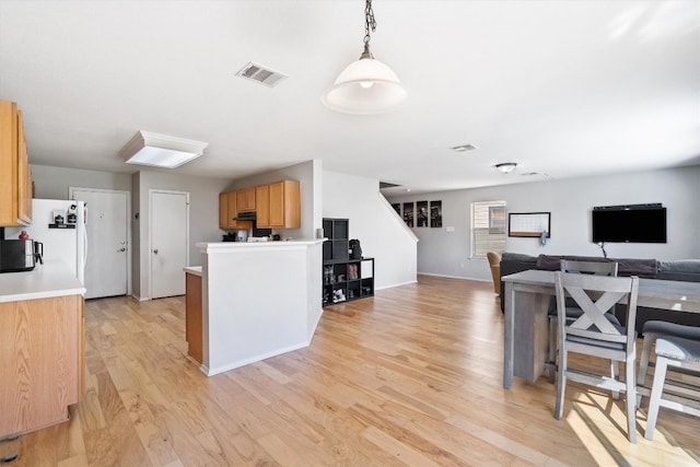 kitchen with decorative light fixtures, light hardwood / wood-style floors, light brown cabinetry, and white refrigerator