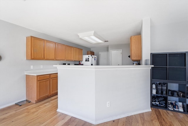 kitchen with white refrigerator with ice dispenser, kitchen peninsula, and light wood-type flooring