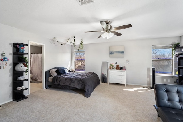 bedroom featuring connected bathroom, light colored carpet, and ceiling fan