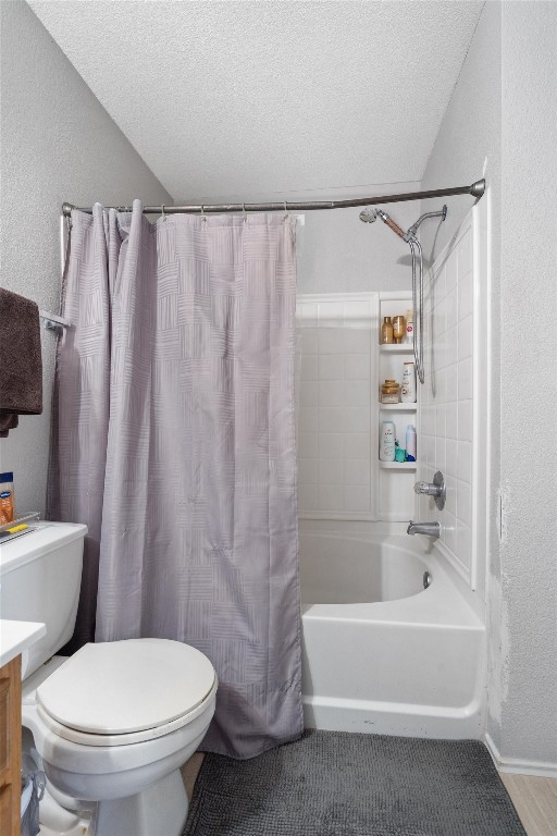 full bathroom with vanity, a textured ceiling, shower / tub combo with curtain, and toilet