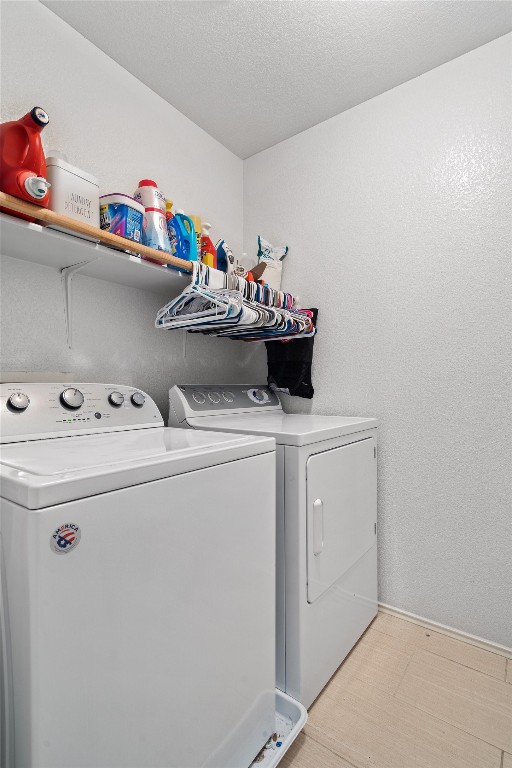 clothes washing area with a textured ceiling and washing machine and clothes dryer