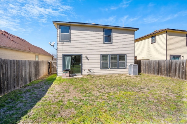 rear view of property with central air condition unit and a lawn