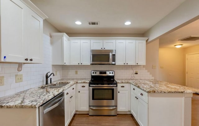 kitchen featuring white cabinets, backsplash, light hardwood / wood-style flooring, and stainless steel appliances