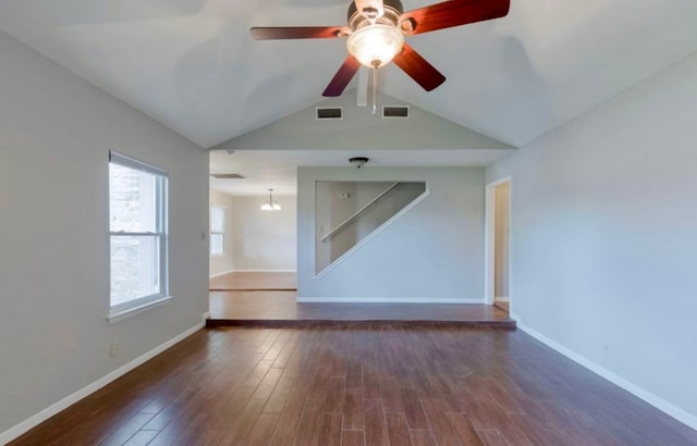 spare room with dark hardwood / wood-style floors, ceiling fan with notable chandelier, and a healthy amount of sunlight