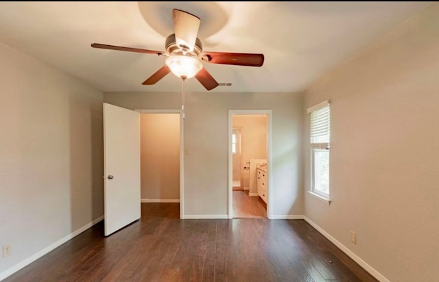 unfurnished bedroom featuring ensuite bath, dark hardwood / wood-style flooring, and ceiling fan