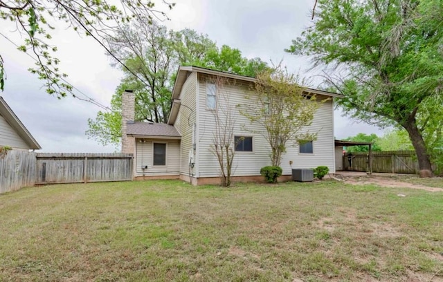 rear view of house with central AC unit and a lawn