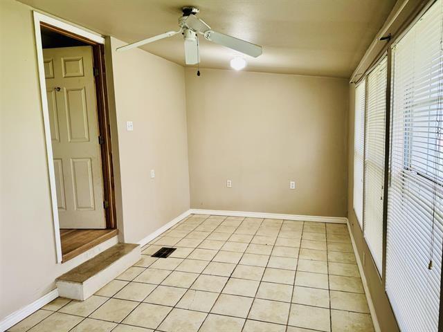 tiled empty room featuring ceiling fan