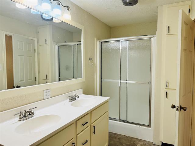 bathroom with vanity, an enclosed shower, and a textured ceiling