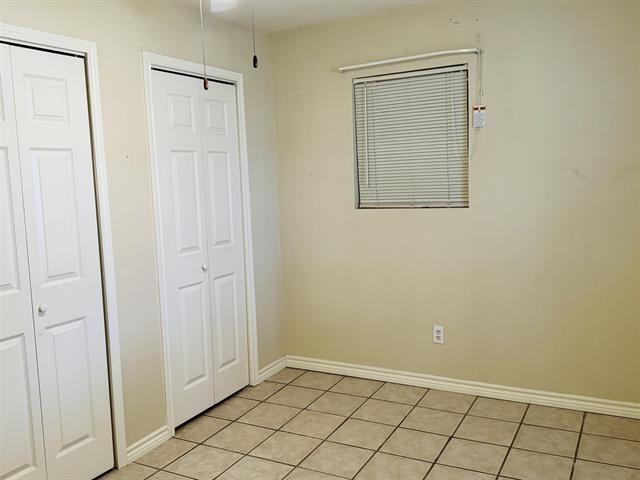 unfurnished bedroom with light tile patterned floors and two closets