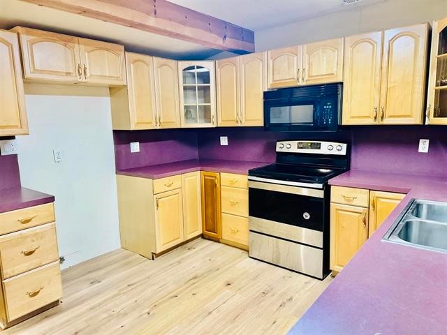 kitchen with electric range, light brown cabinetry, and light hardwood / wood-style floors