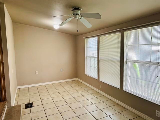 tiled spare room with ceiling fan