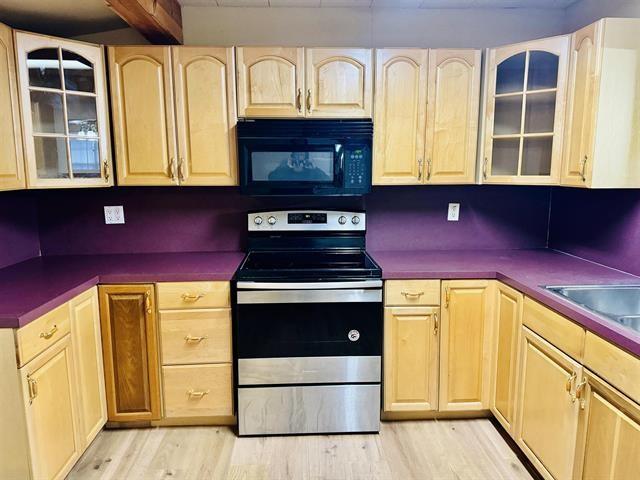 kitchen with light brown cabinets, sink, light hardwood / wood-style floors, and stainless steel electric range