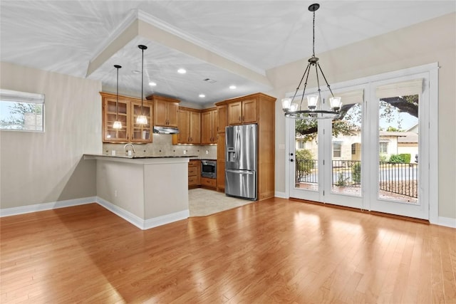 kitchen with hanging light fixtures, stainless steel appliances, light hardwood / wood-style floors, decorative backsplash, and kitchen peninsula