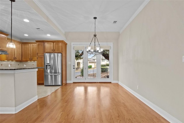 kitchen with stainless steel fridge with ice dispenser, dark stone countertops, light wood-type flooring, pendant lighting, and decorative backsplash