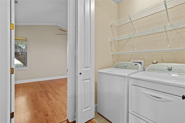 laundry room with crown molding, independent washer and dryer, and light hardwood / wood-style floors