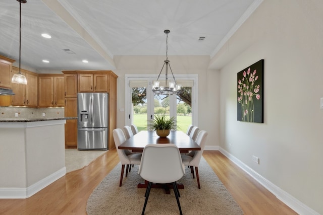 dining space with an inviting chandelier, crown molding, and light hardwood / wood-style floors