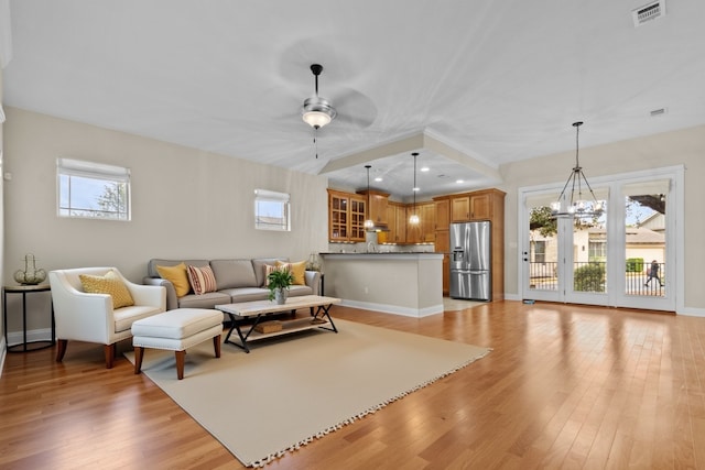 living room with ceiling fan with notable chandelier, plenty of natural light, and light hardwood / wood-style floors