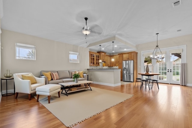 living room with ceiling fan with notable chandelier and light wood-type flooring