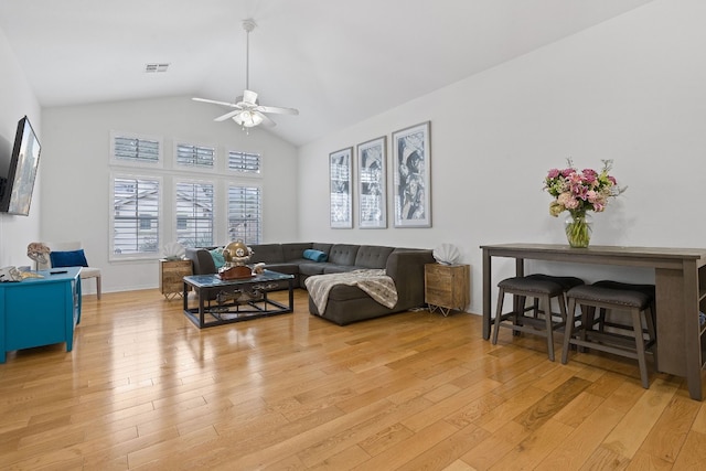 living room with ceiling fan, light hardwood / wood-style floors, and vaulted ceiling