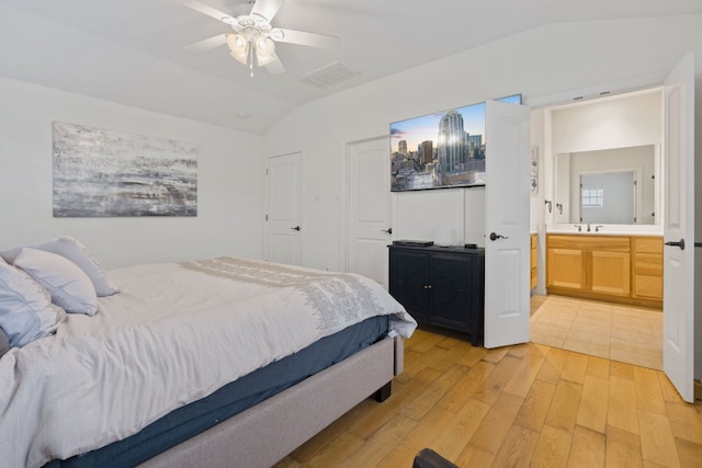 bedroom with ceiling fan, sink, light wood-type flooring, ensuite bath, and vaulted ceiling