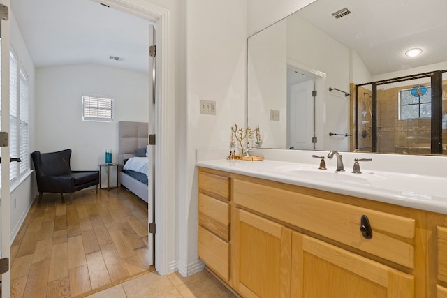 bathroom featuring vaulted ceiling, plenty of natural light, vanity, and wood-type flooring