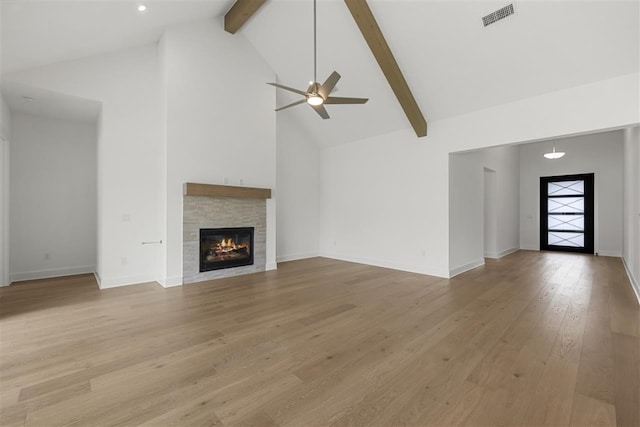 unfurnished living room with a fireplace, beam ceiling, high vaulted ceiling, light hardwood / wood-style floors, and ceiling fan