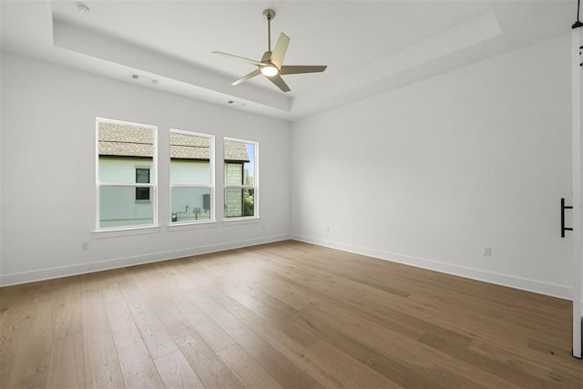 unfurnished room featuring hardwood / wood-style flooring, ceiling fan, and a tray ceiling