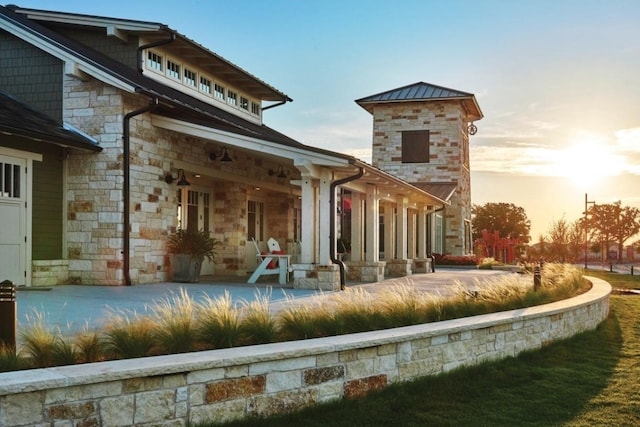 back of house featuring stone siding, metal roof, and a standing seam roof