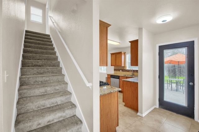 stairway with light tile patterned flooring, sink, and a wealth of natural light