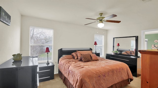 bedroom with light carpet, multiple windows, and ceiling fan