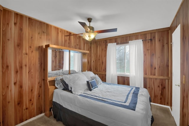 carpeted bedroom featuring wood walls and ceiling fan