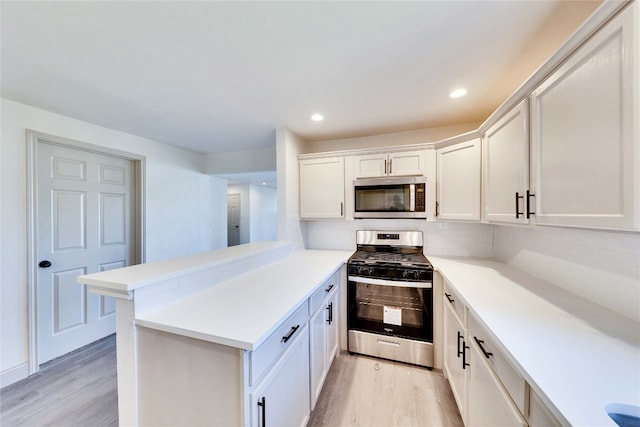 kitchen with light hardwood / wood-style flooring, kitchen peninsula, backsplash, white cabinets, and appliances with stainless steel finishes