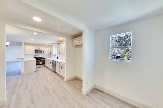 kitchen featuring appliances with stainless steel finishes, white cabinetry, sink, and light hardwood / wood-style flooring