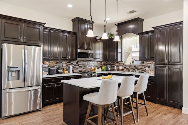 kitchen featuring hanging light fixtures, a breakfast bar, stainless steel appliances, a center island, and tasteful backsplash