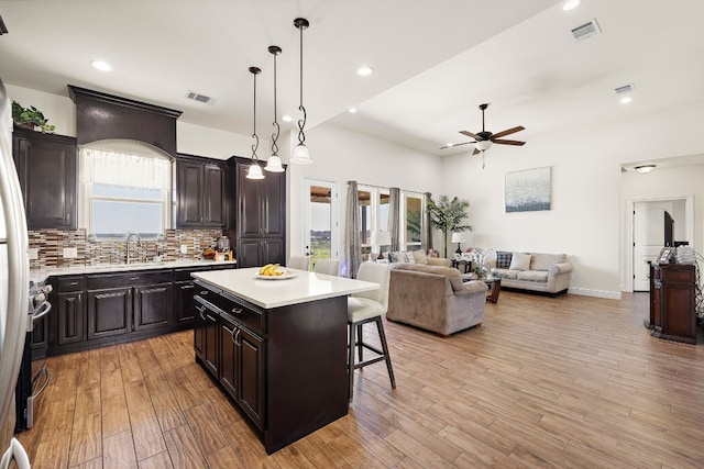 kitchen featuring ceiling fan, plenty of natural light, hanging light fixtures, backsplash, and a center island