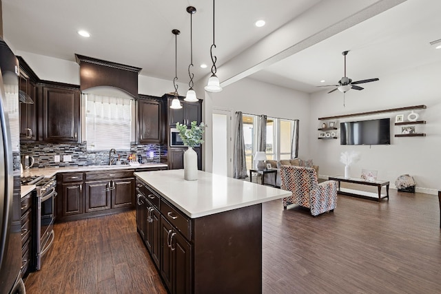 kitchen with stainless steel appliances, a center island, ceiling fan, dark wood-type flooring, and hanging light fixtures