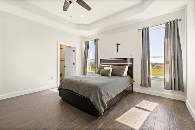 bedroom featuring a raised ceiling, ceiling fan, and multiple windows