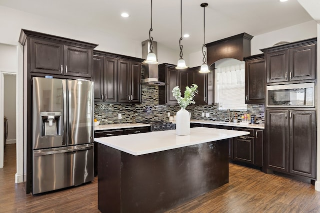 kitchen with a kitchen island, stainless steel refrigerator with ice dispenser, pendant lighting, and wall chimney exhaust hood