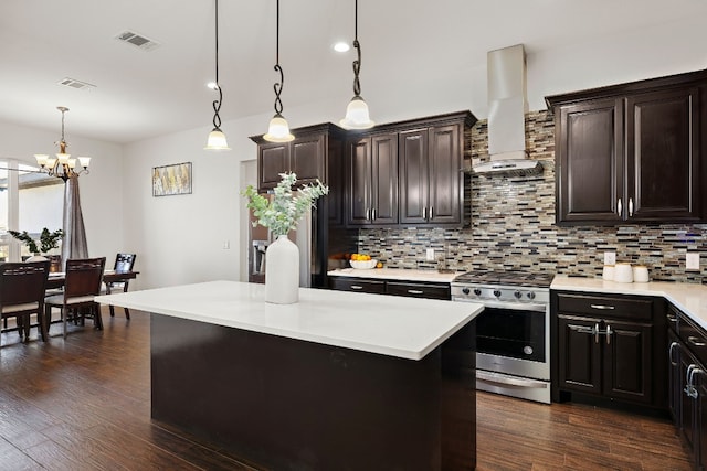 kitchen with decorative light fixtures, gas stove, tasteful backsplash, a notable chandelier, and wall chimney exhaust hood