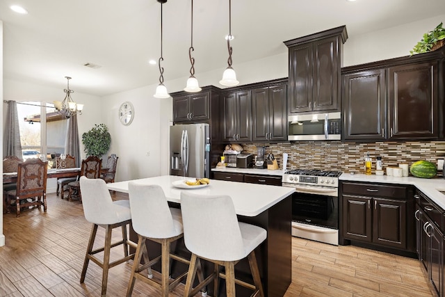 kitchen with pendant lighting, a kitchen breakfast bar, appliances with stainless steel finishes, and an inviting chandelier