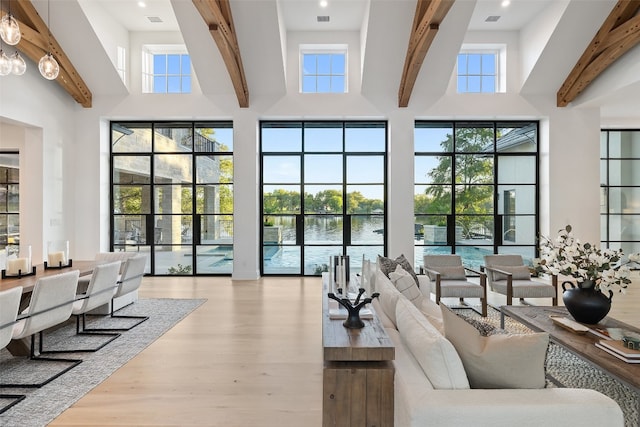 living room with a high ceiling, a water view, and plenty of natural light