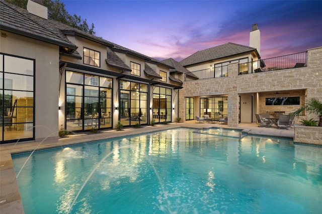 pool at dusk with a patio area