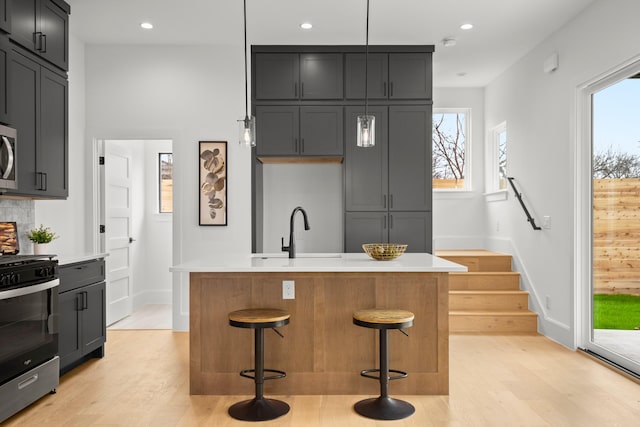 kitchen featuring sink, decorative light fixtures, a kitchen breakfast bar, stainless steel appliances, and a kitchen island with sink