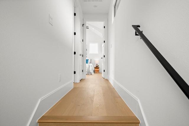 corridor featuring hardwood / wood-style floors and vaulted ceiling